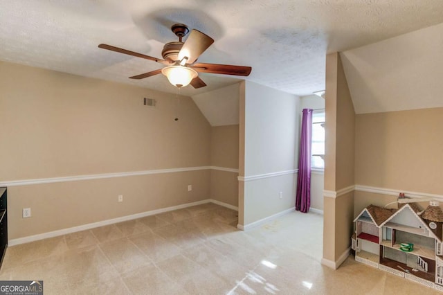 additional living space with light carpet, ceiling fan, vaulted ceiling, and a textured ceiling