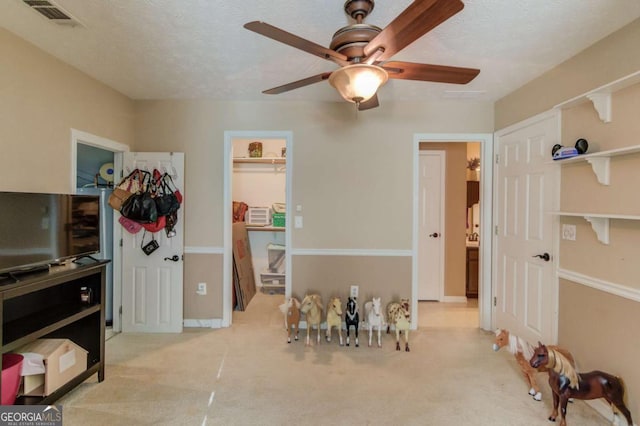 interior space with ceiling fan, a walk in closet, a closet, and a textured ceiling