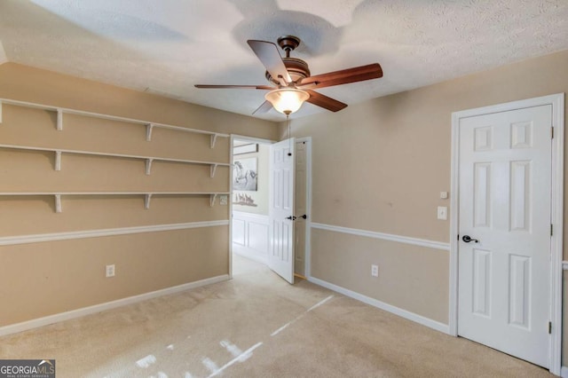 empty room with ceiling fan, light carpet, and a textured ceiling