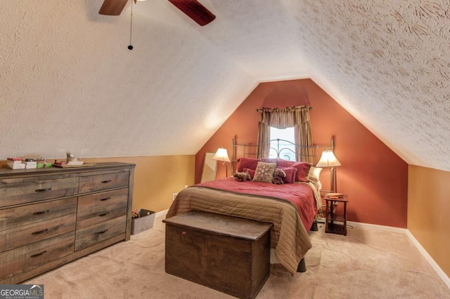 bedroom featuring ceiling fan, vaulted ceiling, light colored carpet, and a textured ceiling