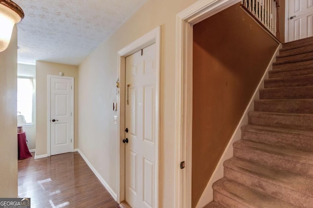 hallway featuring wood-type flooring and a textured ceiling