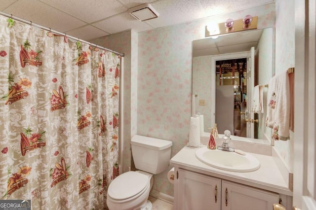 bathroom featuring vanity, toilet, and a drop ceiling