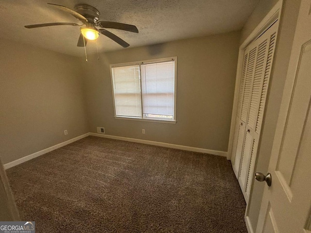 unfurnished bedroom featuring ceiling fan, a closet, a textured ceiling, and dark colored carpet