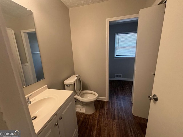 bathroom with wood-type flooring, vanity, a textured ceiling, and toilet