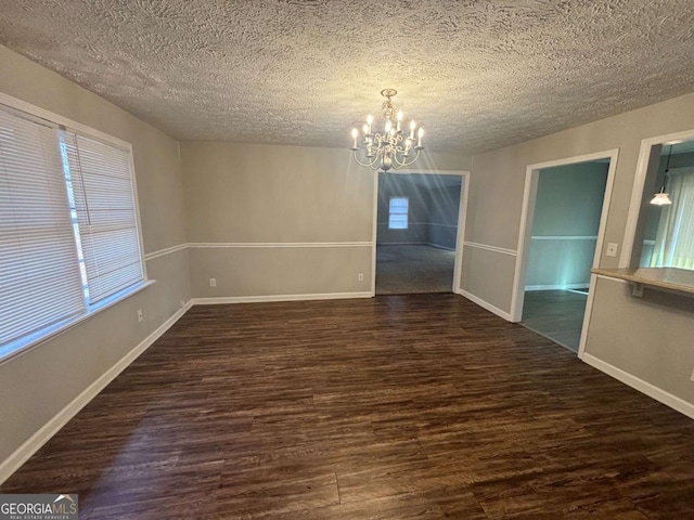 unfurnished dining area featuring an inviting chandelier, dark hardwood / wood-style floors, and a textured ceiling