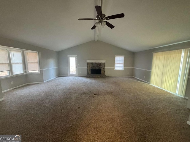 unfurnished living room with lofted ceiling with beams, a healthy amount of sunlight, a fireplace, and carpet flooring