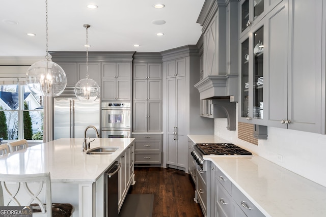 kitchen featuring sink, gray cabinetry, a kitchen breakfast bar, premium appliances, and decorative light fixtures