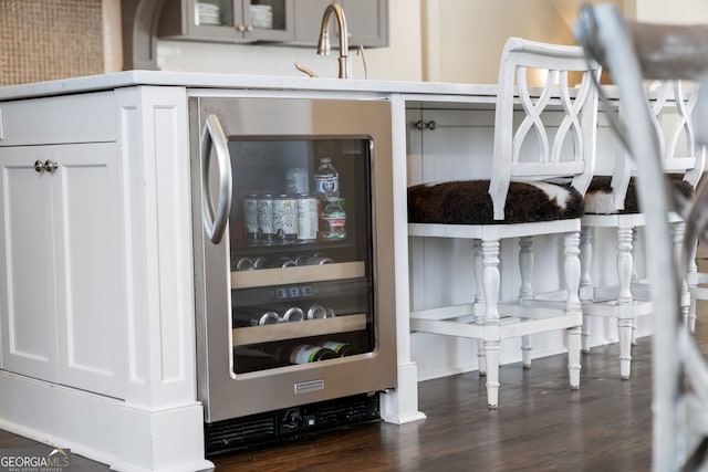 details with beverage cooler, dark hardwood / wood-style flooring, sink, and white cabinets