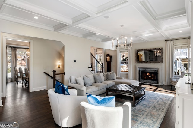 living room featuring a chandelier, dark wood-type flooring, a wealth of natural light, and a fireplace