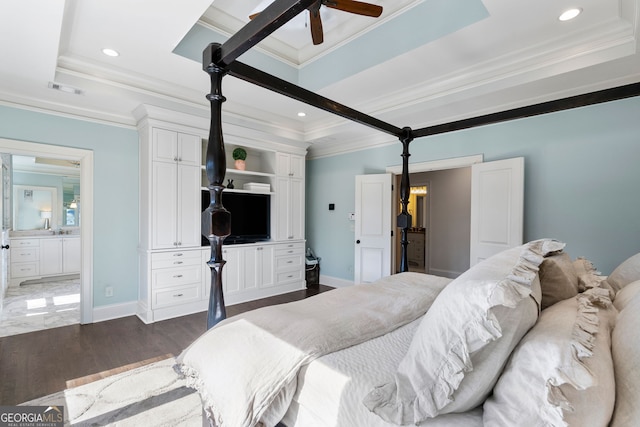 bedroom with dark hardwood / wood-style floors, ornamental molding, a tray ceiling, and connected bathroom