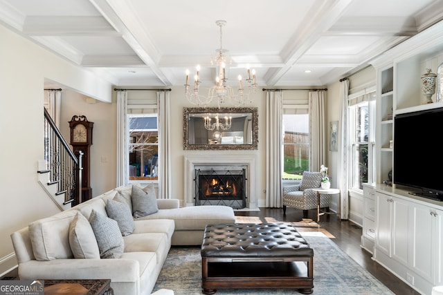 living room featuring dark wood-type flooring, coffered ceiling, beam ceiling, a notable chandelier, and a premium fireplace