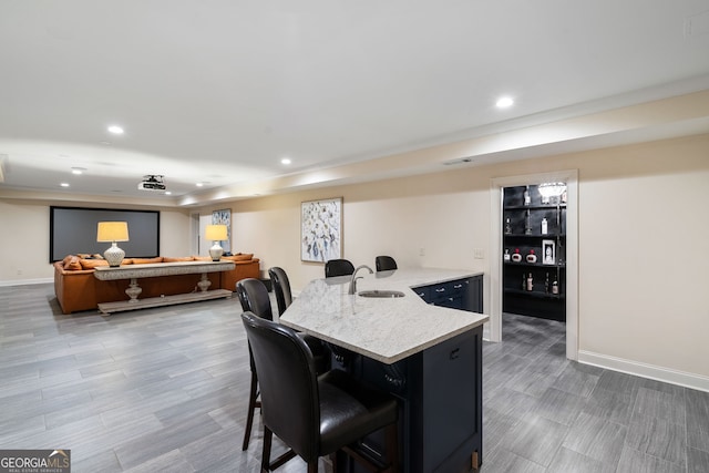 kitchen featuring hardwood / wood-style flooring, light stone countertops, sink, and a kitchen bar