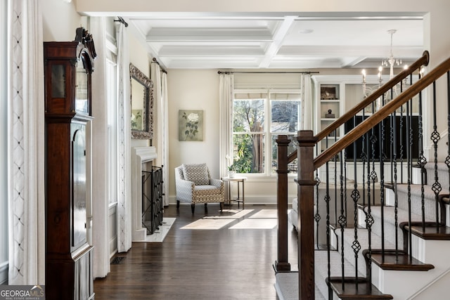 interior space with dark wood-type flooring, beam ceiling, coffered ceiling, a notable chandelier, and a high end fireplace