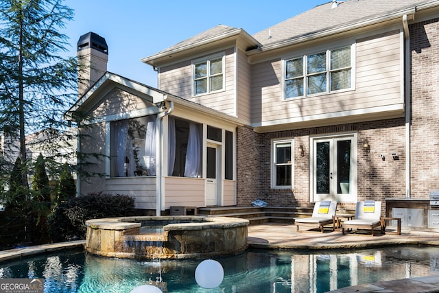 rear view of house featuring a swimming pool with hot tub, a sunroom, french doors, and a patio area