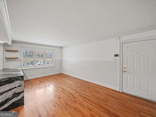 unfurnished living room with hardwood / wood-style floors and crown molding