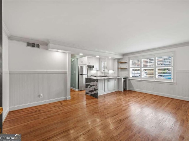 unfurnished living room with ornamental molding, sink, and light wood-type flooring