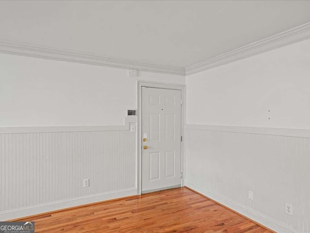 empty room featuring crown molding and wood-type flooring