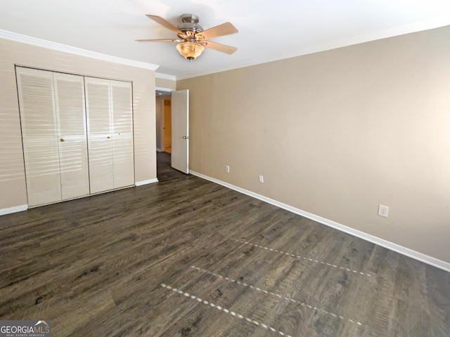 unfurnished bedroom featuring crown molding, ceiling fan, dark hardwood / wood-style flooring, and a closet