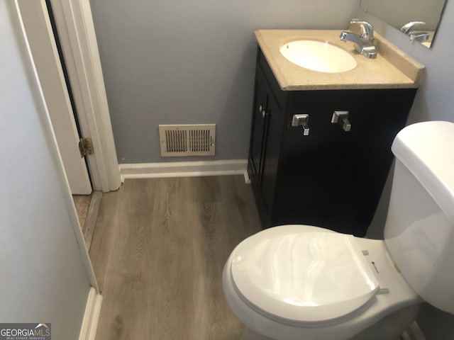 5250 Hollyhock Rd, Douglasville, GA 30135 - half bathroom featuring toilet, wood finished floors, vanity, and baseboards