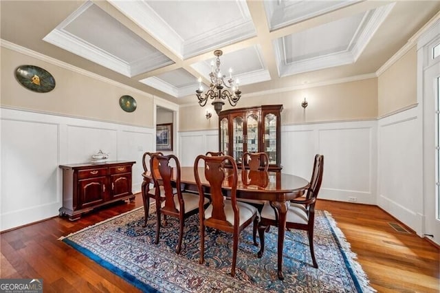 dining area featuring beamed ceiling, wood-type flooring, ornamental molding, coffered ceiling, and a notable chandelier