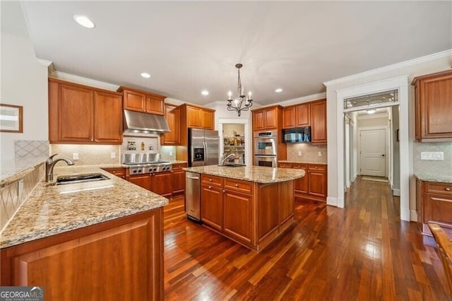 kitchen featuring a kitchen island, pendant lighting, sink, stainless steel appliances, and light stone countertops