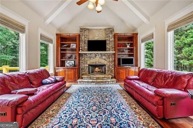 living room with lofted ceiling with beams, wood-type flooring, a stone fireplace, and ceiling fan