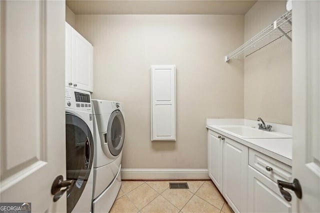 clothes washing area featuring cabinets, washing machine and clothes dryer, light tile patterned flooring, and sink