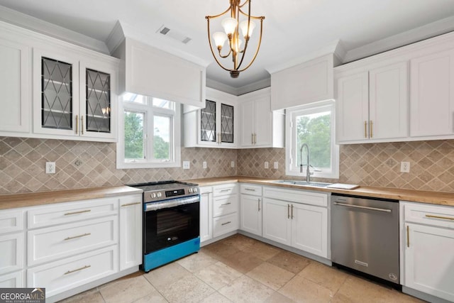 kitchen featuring sink, appliances with stainless steel finishes, backsplash, white cabinets, and decorative light fixtures