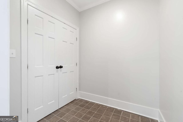 doorway with ornamental molding and dark tile patterned flooring