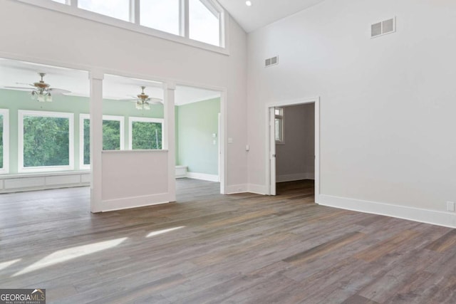 unfurnished living room with ceiling fan, dark hardwood / wood-style flooring, high vaulted ceiling, and a wealth of natural light