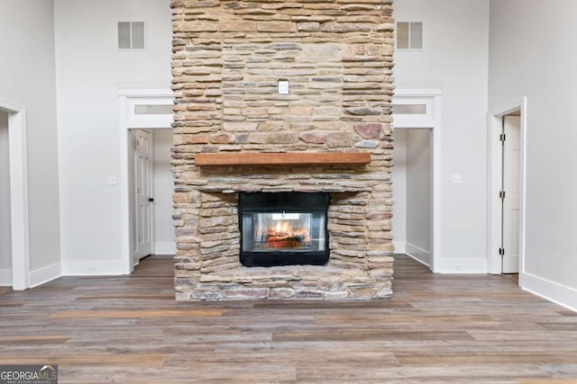 unfurnished living room featuring hardwood / wood-style flooring, a fireplace, and a high ceiling