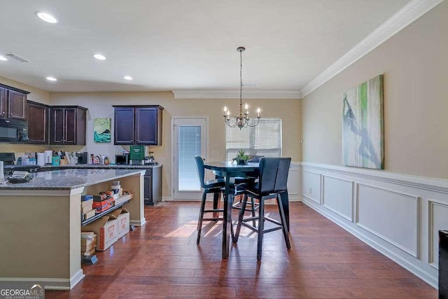 dining area with dark hardwood / wood-style flooring, ornamental molding, and an inviting chandelier