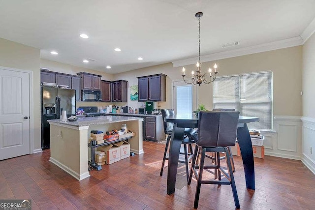 kitchen with hanging light fixtures, a center island, dark brown cabinetry, black appliances, and dark hardwood / wood-style flooring