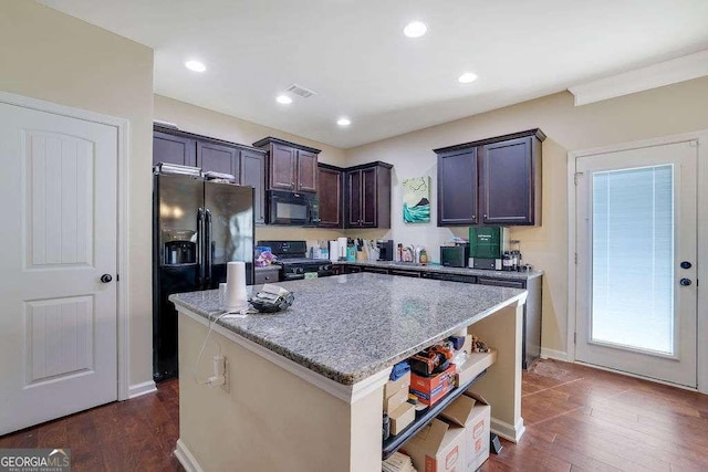 kitchen featuring dark brown cabinetry, dark hardwood / wood-style floors, a kitchen island, light stone countertops, and black appliances