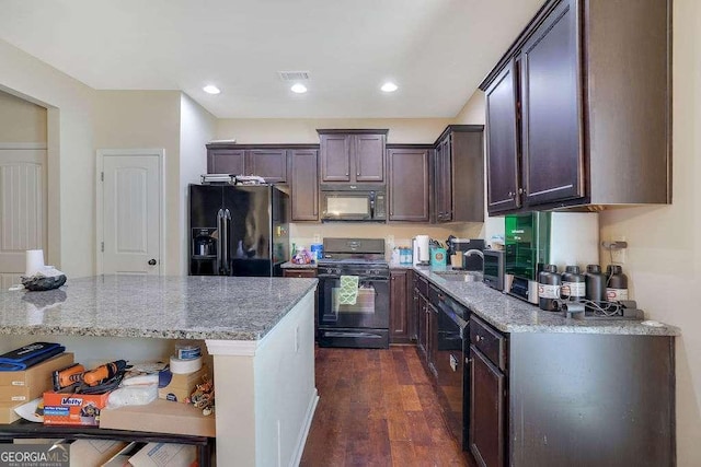 kitchen featuring dark brown cabinetry, sink, dark hardwood / wood-style flooring, light stone countertops, and black appliances