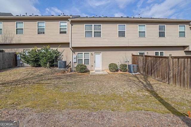 rear view of property featuring cooling unit and a lawn