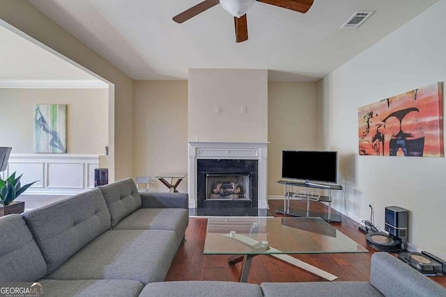 living room featuring hardwood / wood-style flooring, ceiling fan, a high end fireplace, and crown molding