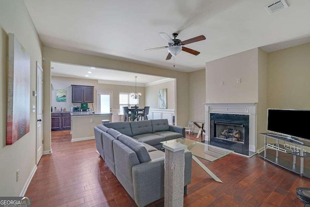 living room featuring a premium fireplace, ceiling fan with notable chandelier, and dark hardwood / wood-style flooring