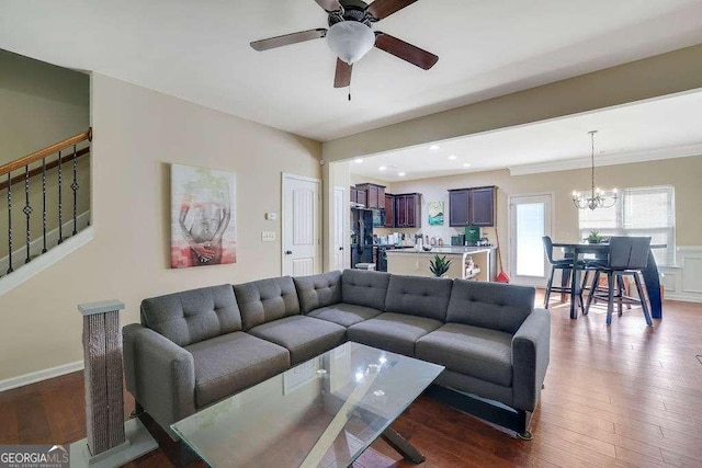 living room with dark hardwood / wood-style flooring and ceiling fan with notable chandelier