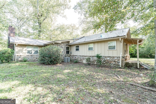 back of property with central AC unit and a lawn