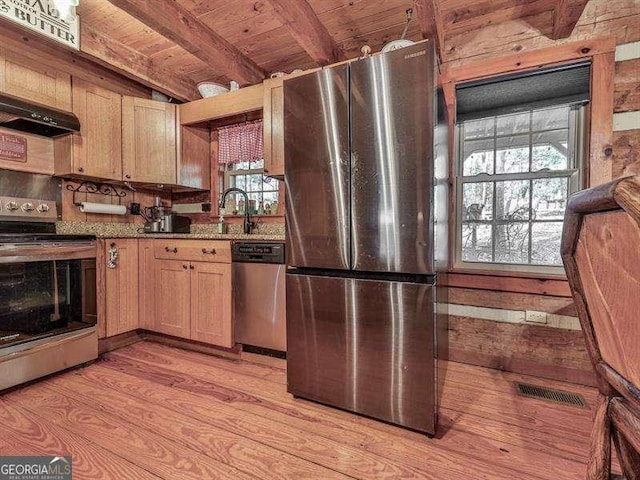 kitchen with ventilation hood, stone counters, stainless steel appliances, beam ceiling, and light hardwood / wood-style floors