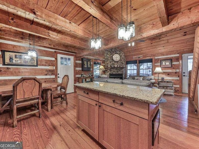 kitchen featuring a kitchen island, wood walls, hanging light fixtures, light stone countertops, and wooden ceiling