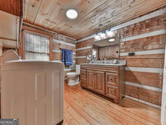 bathroom with wood walls, washer / clothes dryer, wood-type flooring, vanity, and wooden ceiling