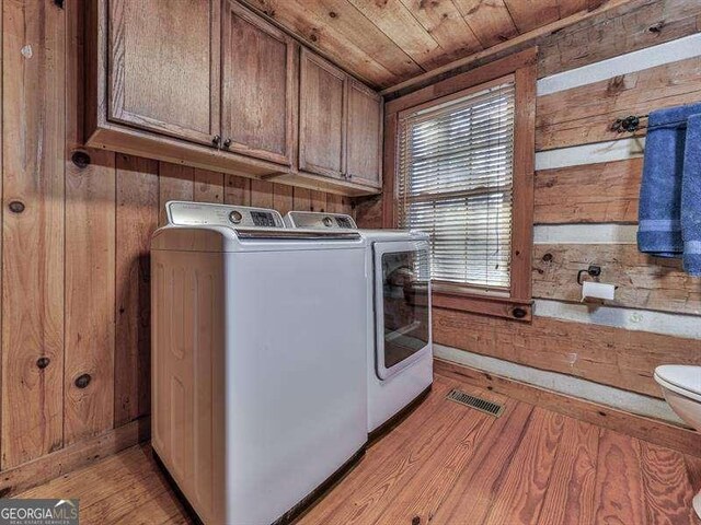 laundry room featuring wood ceiling, light hardwood / wood-style flooring, washing machine and dryer, and wood walls