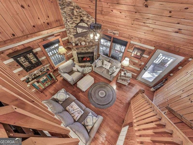 unfurnished living room featuring ceiling fan, a towering ceiling, a stone fireplace, and wooden ceiling