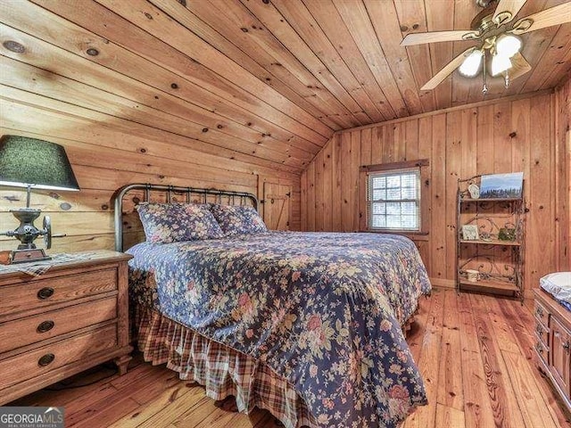 bedroom featuring vaulted ceiling, wood ceiling, light hardwood / wood-style floors, and wood walls