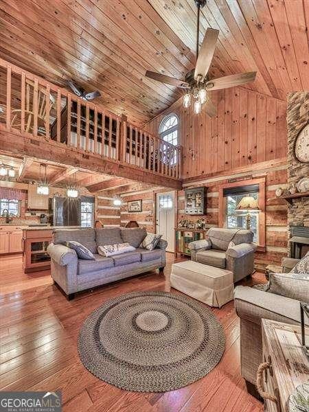 living room featuring hardwood / wood-style floors, a stone fireplace, wooden ceiling, and ceiling fan