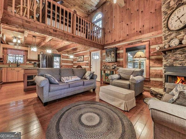 living room with dark hardwood / wood-style flooring, sink, wood ceiling, and a stone fireplace