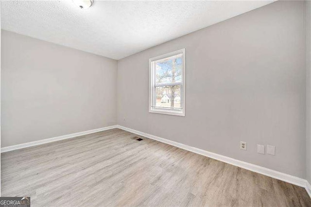 unfurnished room featuring light hardwood / wood-style floors and a textured ceiling