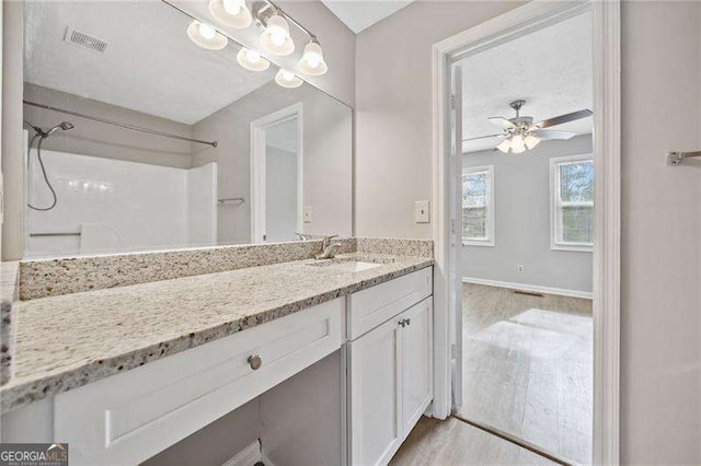 bathroom featuring a shower, wood-type flooring, vanity, and ceiling fan